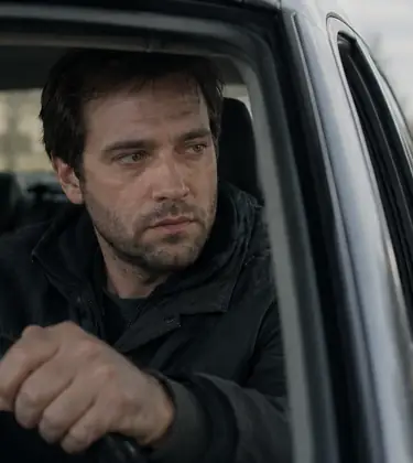 Worried man gripping the steering wheel as a police car approaches behind his vehicle.