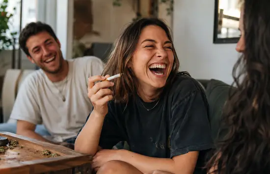 Friends laughing together in a cozy living room during a relaxed cannabis session.